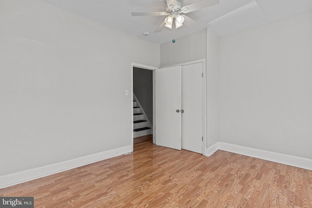 unfurnished bedroom featuring baseboards, a ceiling fan, light wood-style floors, and a closet