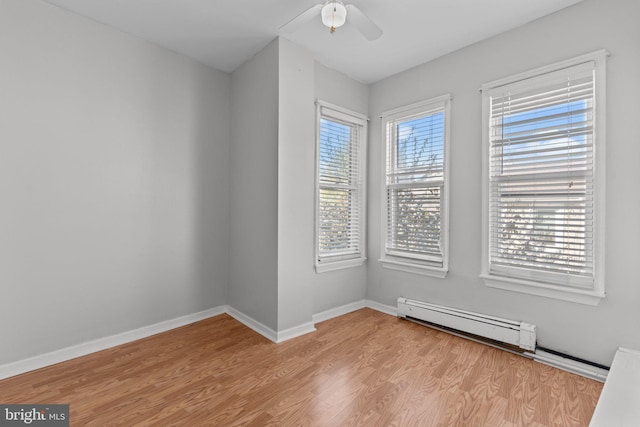 spare room featuring baseboard heating, baseboards, ceiling fan, and light wood-style flooring