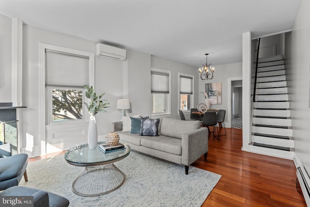 living room featuring stairway, an AC wall unit, a baseboard radiator, wood finished floors, and a notable chandelier