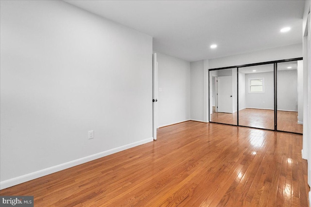 unfurnished bedroom featuring a closet, baseboards, light wood finished floors, and recessed lighting