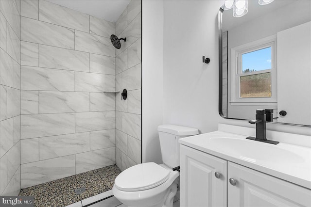 bathroom with toilet, vanity, and a tile shower