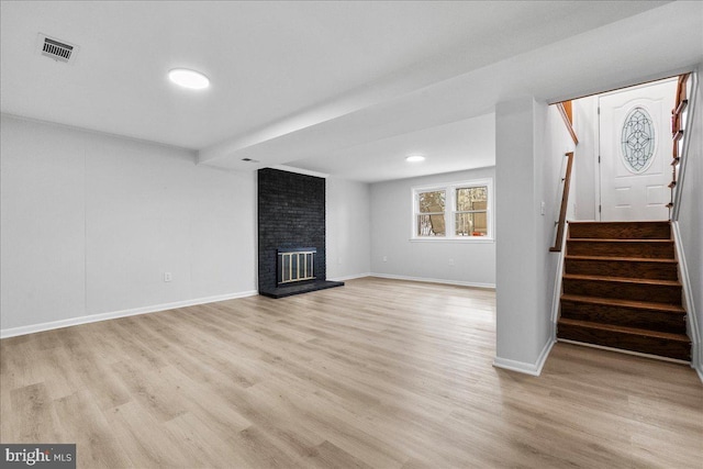 unfurnished living room with baseboards, visible vents, light wood-style floors, and stairway
