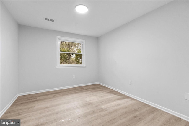 spare room featuring light wood finished floors, baseboards, and visible vents
