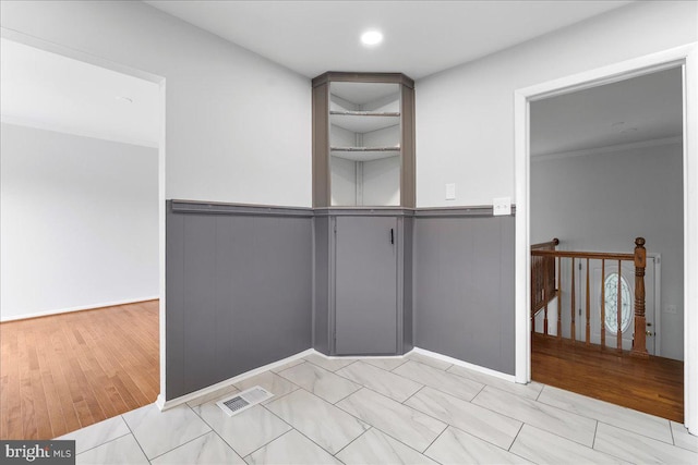 empty room with visible vents, wainscoting, and wood finished floors