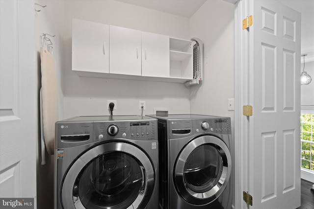 clothes washing area with washing machine and dryer, cabinet space, and wood finished floors