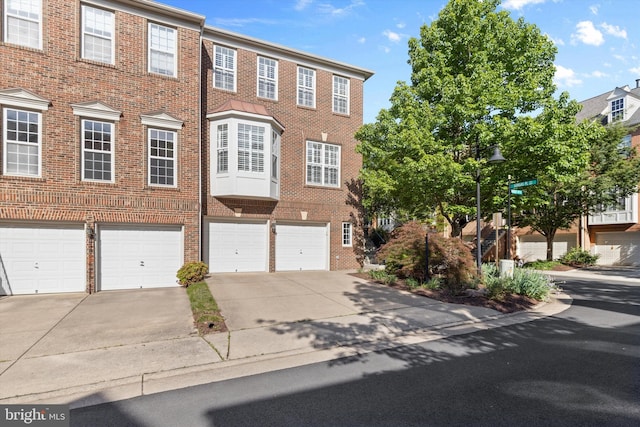 view of property with driveway, brick siding, and an attached garage
