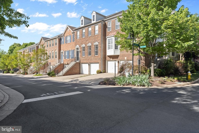 view of property featuring a garage, driveway, and stairway