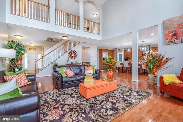 living area with a high ceiling, hardwood / wood-style flooring, and stairway