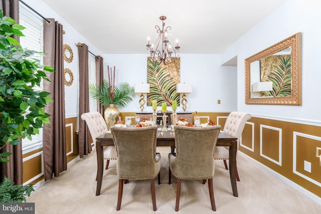dining room with a wainscoted wall, a notable chandelier, and light carpet