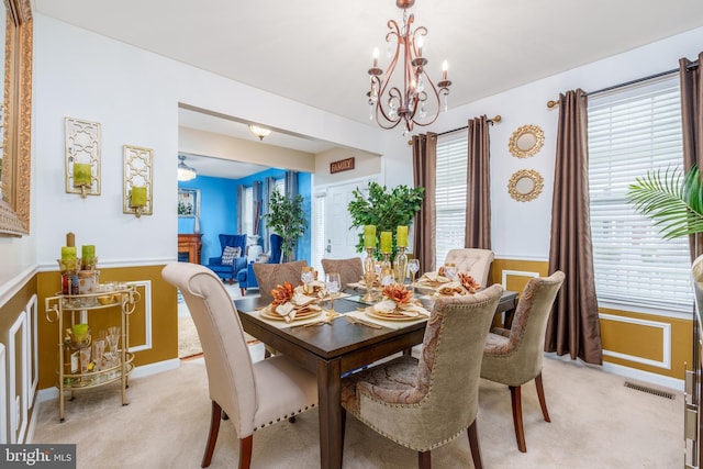 dining space with visible vents, wainscoting, an inviting chandelier, and light carpet