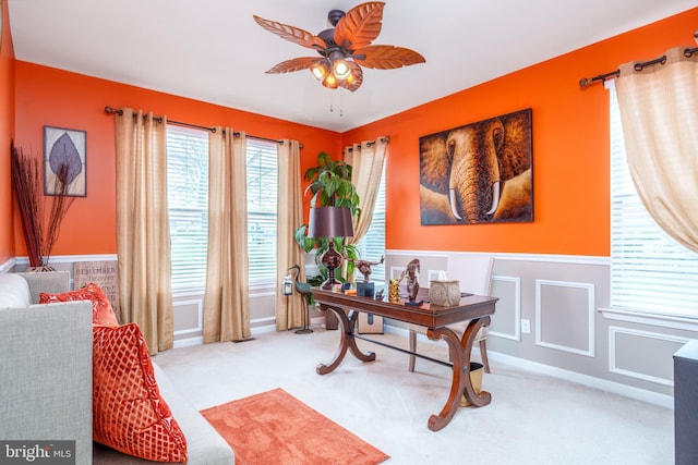 carpeted office space featuring ceiling fan and a wainscoted wall