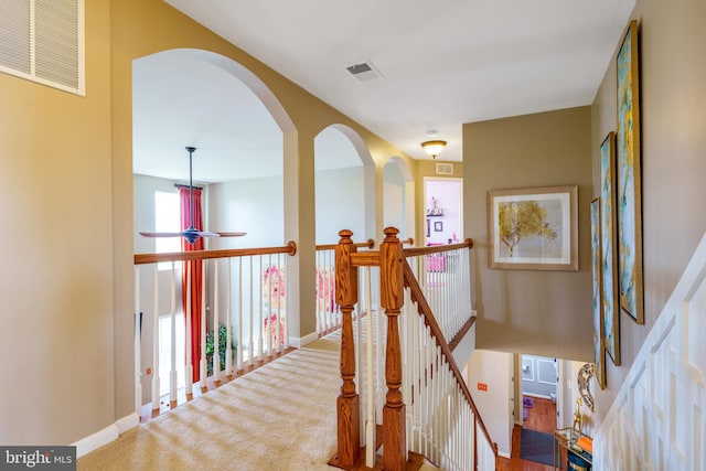 hallway featuring visible vents, baseboards, and an upstairs landing