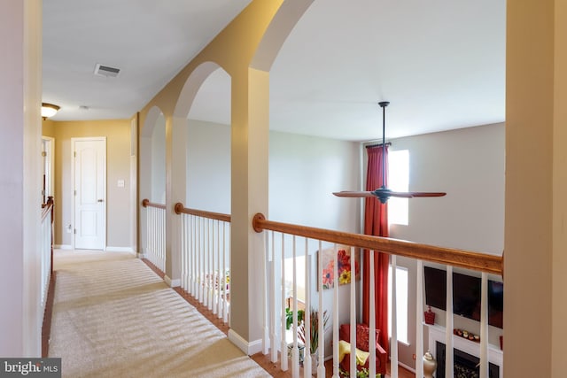 hallway with visible vents, baseboards, arched walkways, and carpet flooring