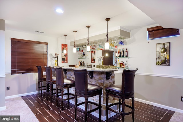 bar featuring indoor wet bar, baseboards, visible vents, and wood tiled floor