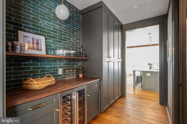 indoor dry bar featuring beverage cooler, light wood-style floors, and tasteful backsplash