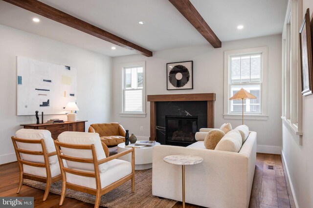 living area with wood finished floors, beamed ceiling, baseboards, a high end fireplace, and recessed lighting