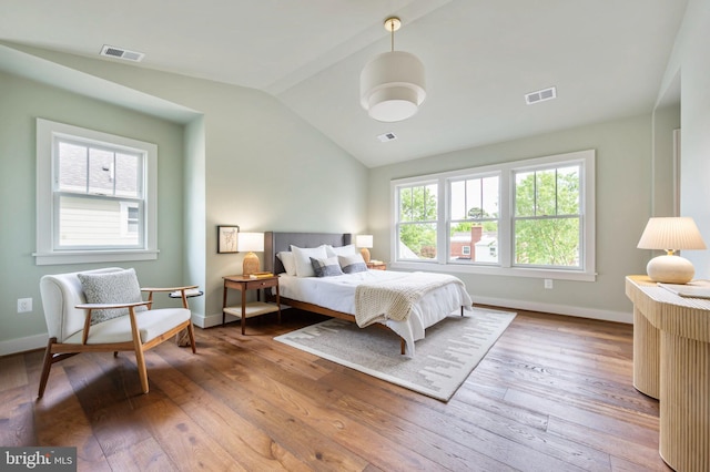 bedroom with vaulted ceiling, wood-type flooring, and baseboards