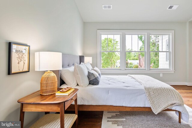 bedroom featuring multiple windows, wood finished floors, and baseboards