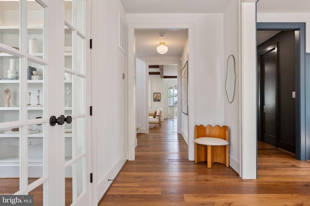 hall featuring wood finished floors, french doors, and baseboards