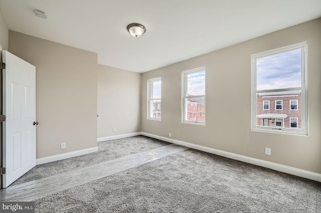 carpeted empty room featuring baseboards