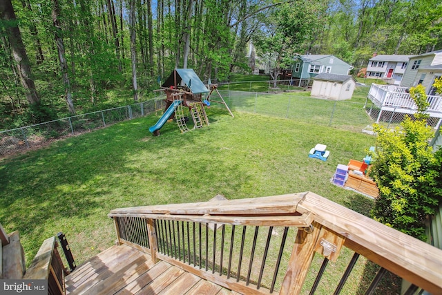 view of yard featuring a playground, a shed, a fenced backyard, and a deck