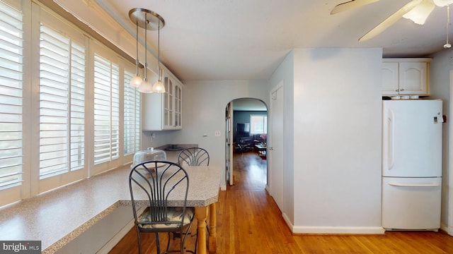 6103 Manor Rd, Clinton, MD 20735 - dining room with arched walkways, light wood-style flooring, a ceiling fan, and baseboards
