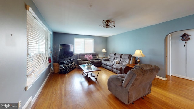 6103 Manor Rd, Clinton, MD 20735 - living room featuring arched walkways, wood finished floors, and baseboards