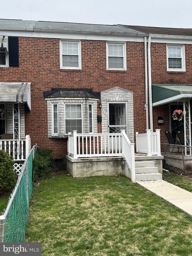 multi unit property with fence, brick siding, and a front yard