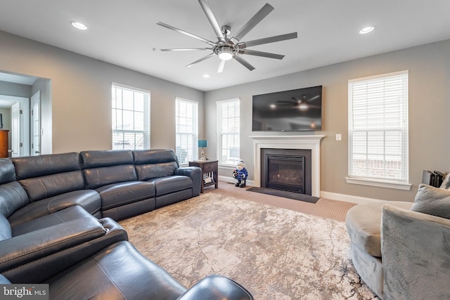 carpeted living room with ceiling fan, recessed lighting, and a fireplace with flush hearth