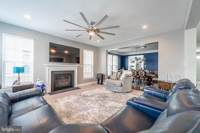 living room featuring a glass covered fireplace, recessed lighting, baseboards, and ceiling fan