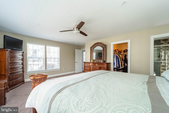 carpeted bedroom with a closet, baseboards, a ceiling fan, a walk in closet, and connected bathroom