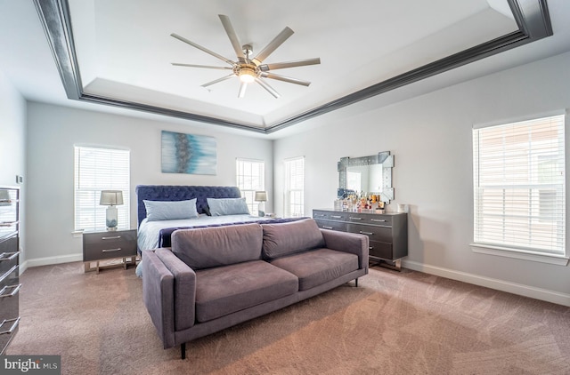 carpeted bedroom featuring a tray ceiling, baseboards, ornamental molding, and a ceiling fan