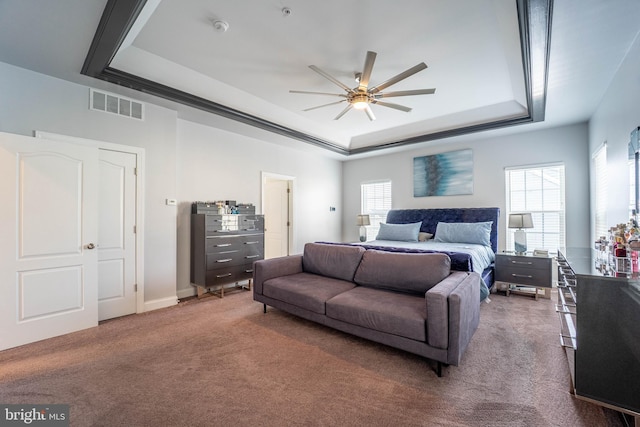 bedroom with carpet floors, visible vents, multiple windows, and a raised ceiling
