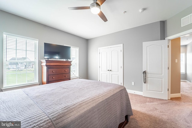 carpeted bedroom featuring a closet, visible vents, multiple windows, and baseboards