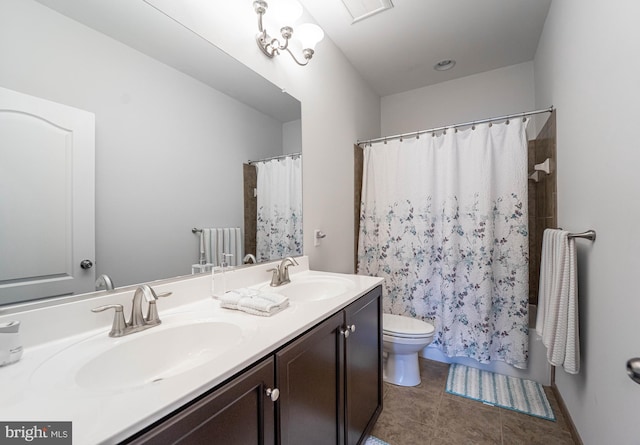 full bath with a sink, toilet, double vanity, and tile patterned flooring