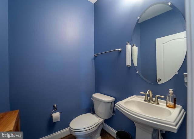 bathroom featuring baseboards, a sink, and toilet