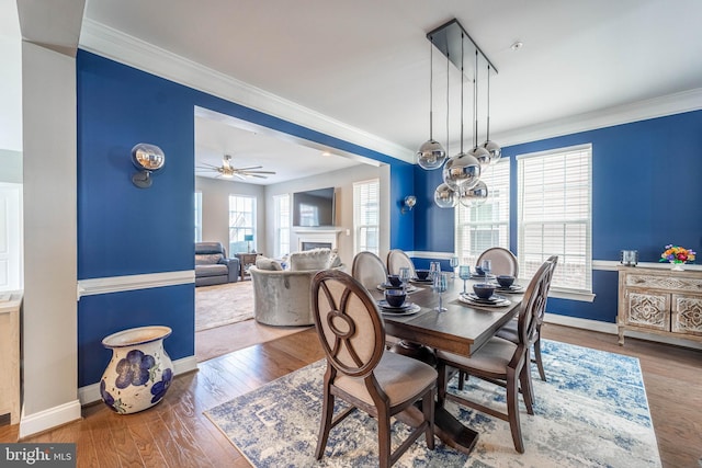 dining room featuring a fireplace, hardwood / wood-style floors, baseboards, and crown molding