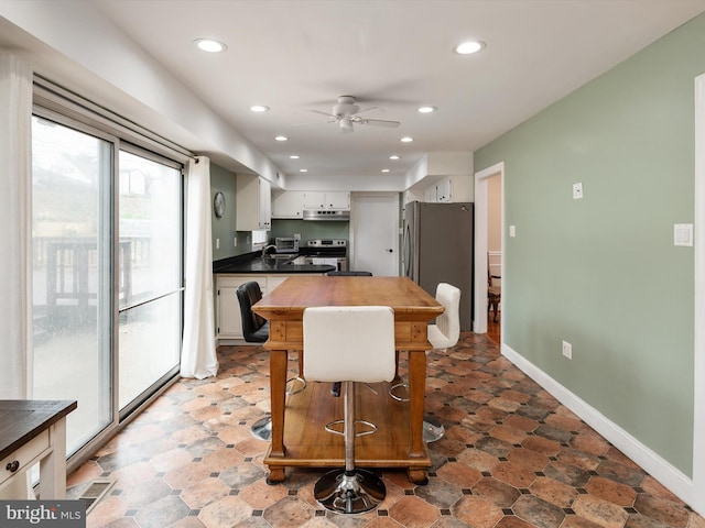 kitchen with dark countertops, a ceiling fan, under cabinet range hood, recessed lighting, and stainless steel appliances