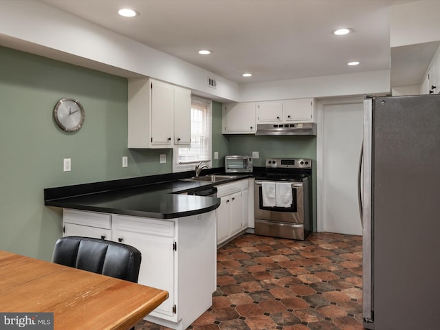 kitchen with a peninsula, dark countertops, white cabinets, under cabinet range hood, and stainless steel appliances