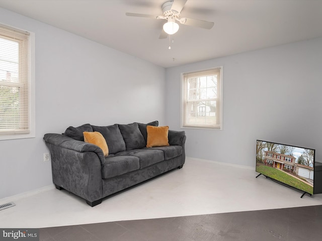 living area with visible vents, baseboards, and a ceiling fan