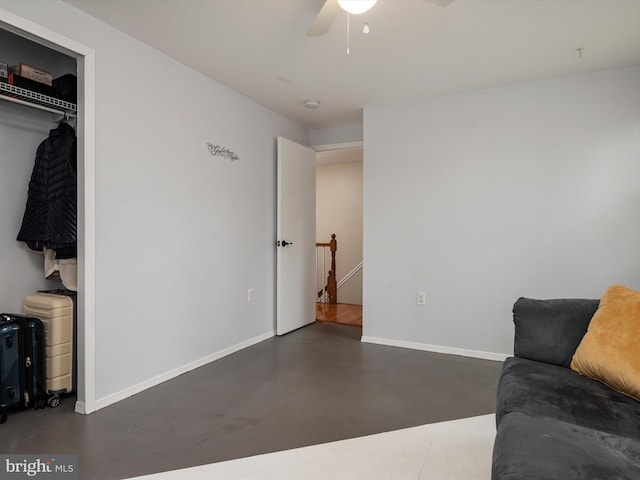 living area featuring finished concrete flooring, baseboards, and a ceiling fan