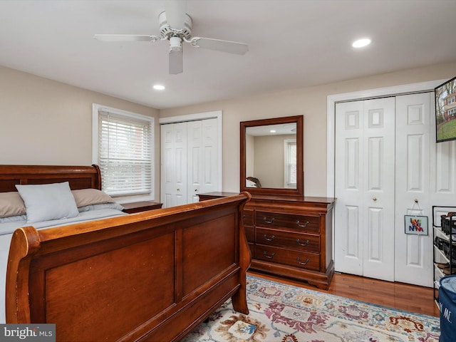 bedroom featuring recessed lighting, ceiling fan, two closets, and wood finished floors