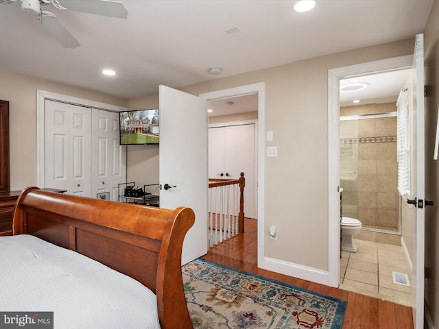 bedroom with a closet, baseboards, connected bathroom, visible vents, and wood finished floors