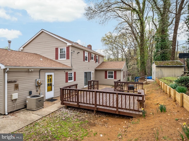 back of property with a shingled roof, a deck, a shed, an outdoor structure, and central air condition unit