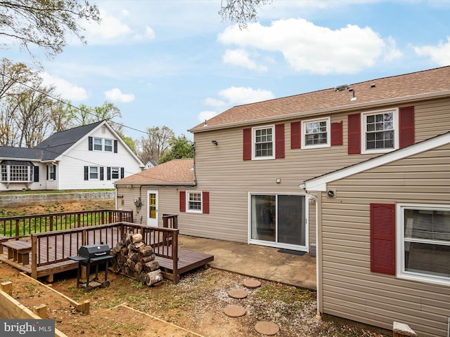 rear view of house featuring a wooden deck and a shingled roof