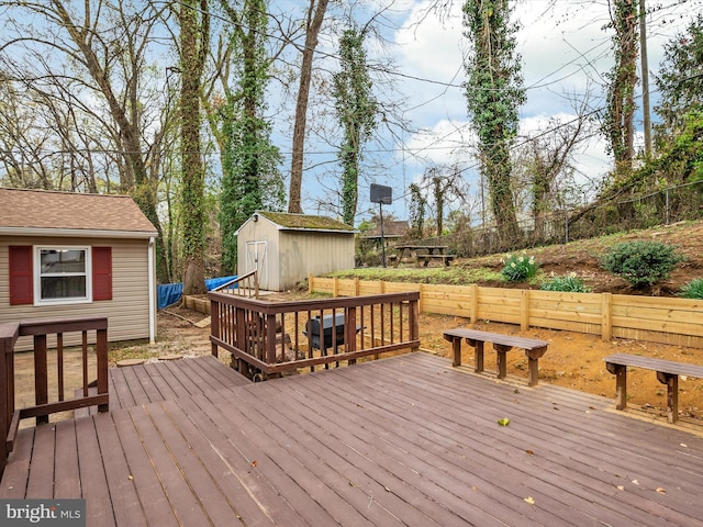 wooden deck featuring a shed, fence, and an outdoor structure