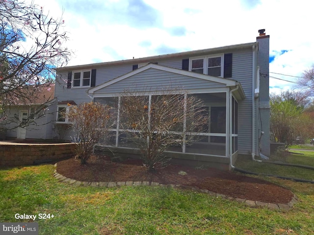 back of property with a yard, a sunroom, and a chimney