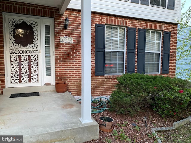 entrance to property with covered porch and brick siding