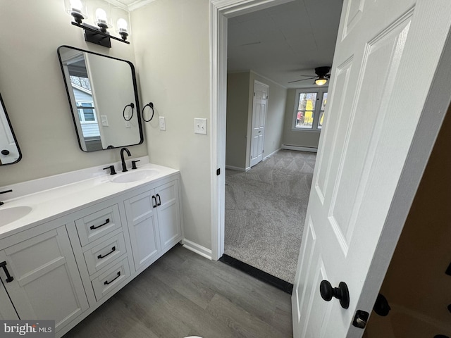 full bath with a sink, a ceiling fan, baseboard heating, baseboards, and double vanity