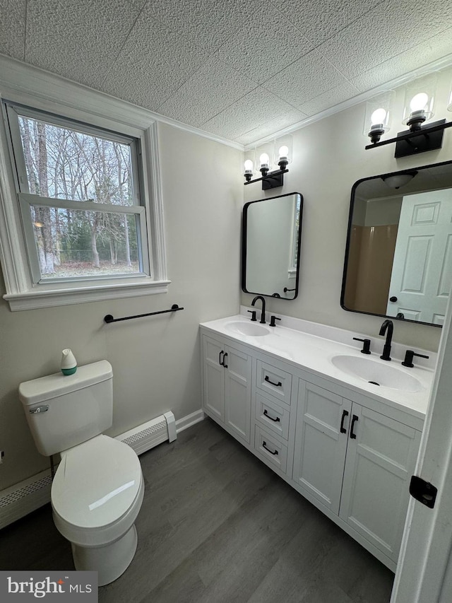 full bathroom with toilet, a sink, a baseboard heating unit, and wood finished floors